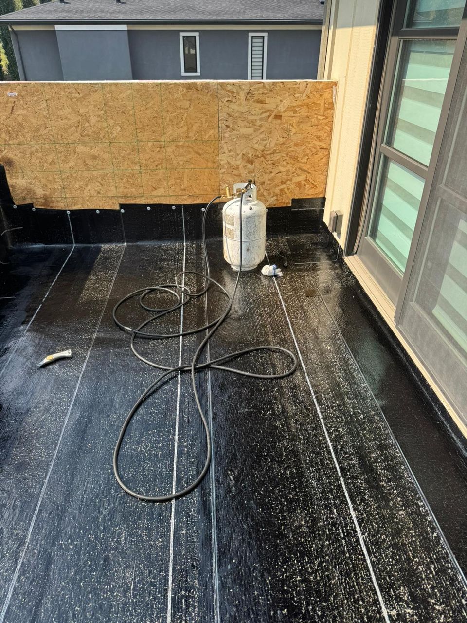 Balcony membrane replacement in Calgary with a propane torch and hose on the deck