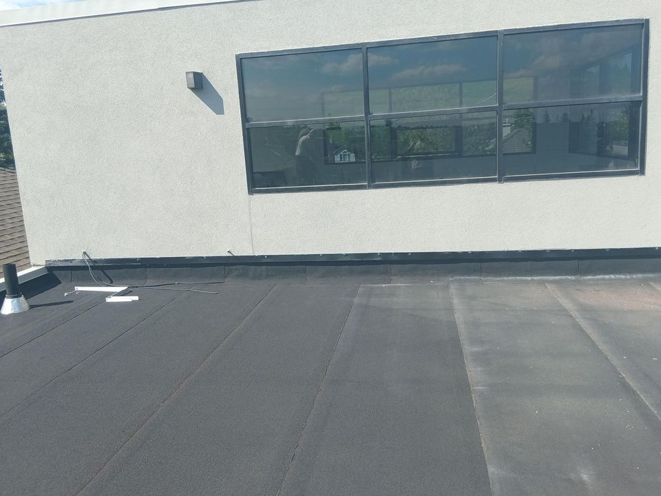 Flat roof membrane carried up the base of a stucco wall on a modern Calgary home