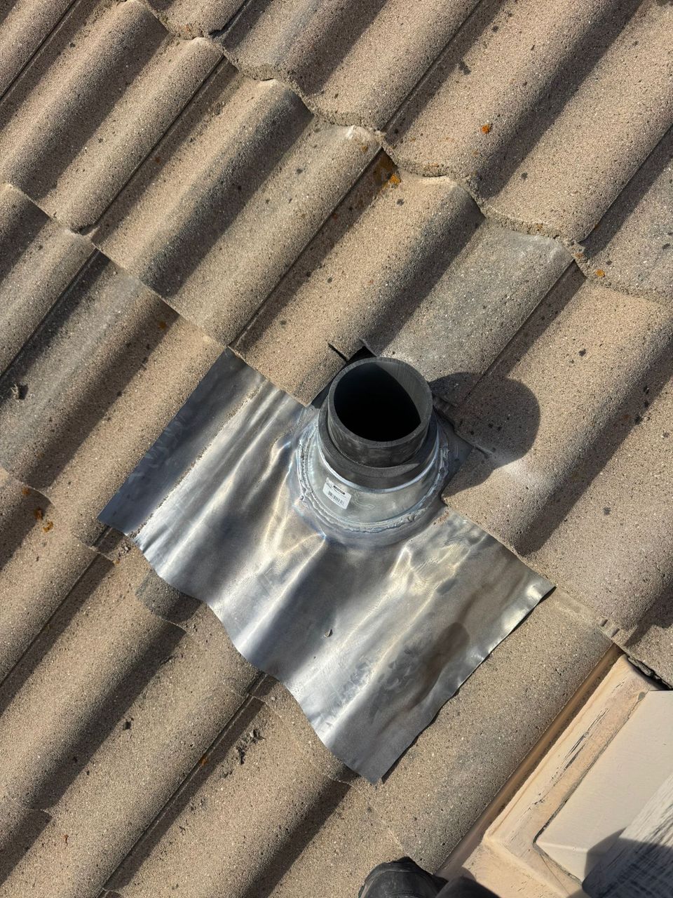 Lead vent flashing formed over the wave of a concrete tile