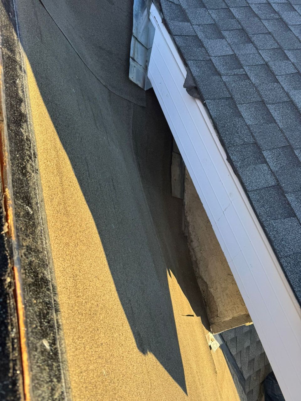 Low-slope roof membrane at the junction of a wall and a shingle roof