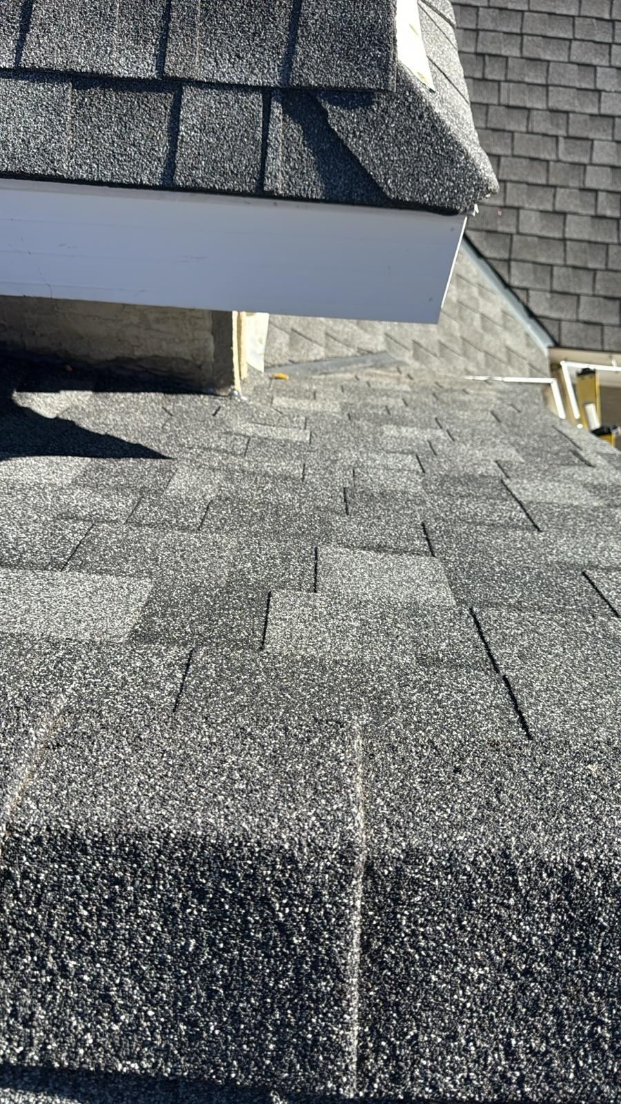 New asphalt shingles installed at a dormer wall during a roof repair