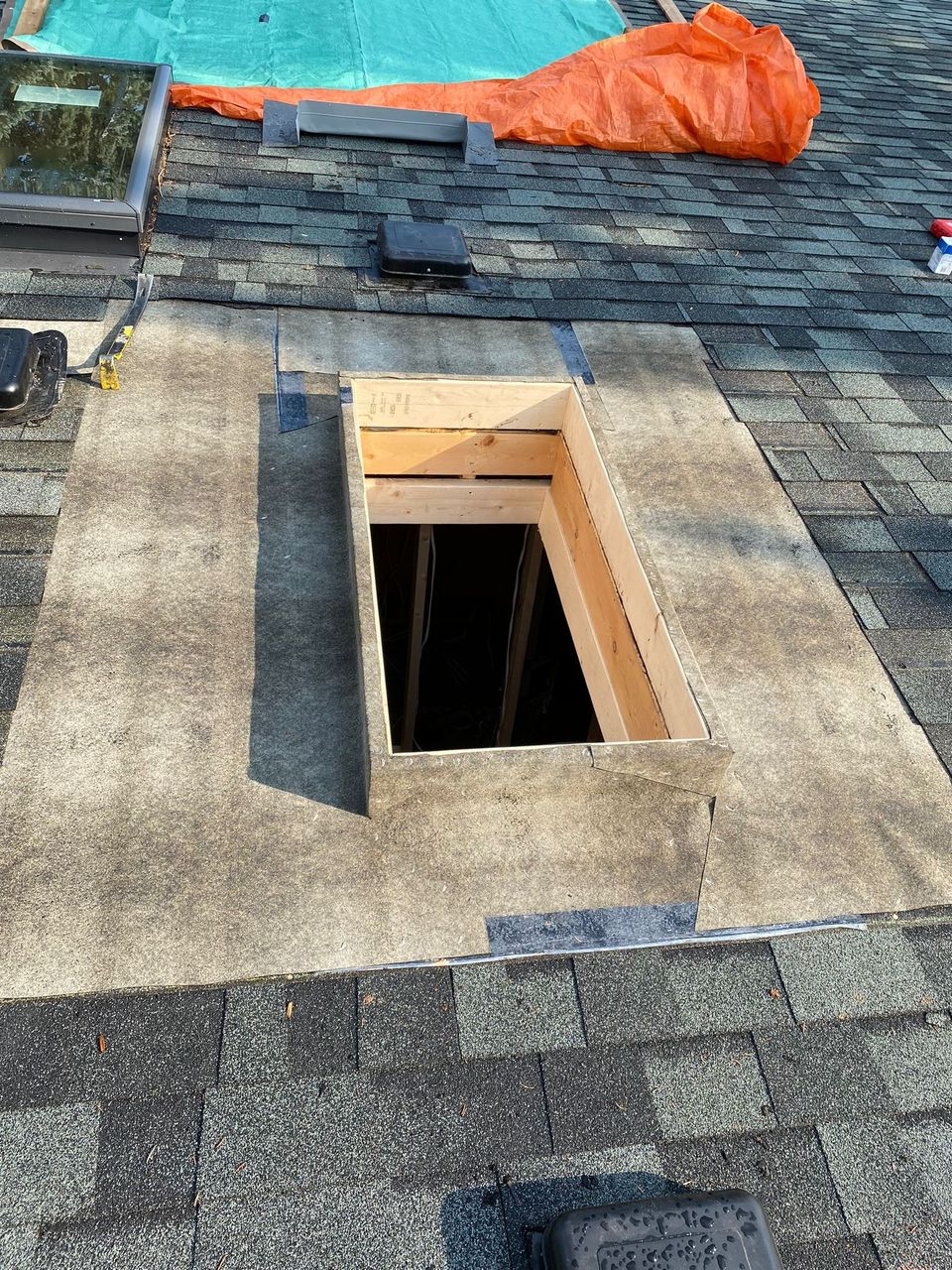 Old skylight removed from a shingle roof with a new wood curb framed in the opening