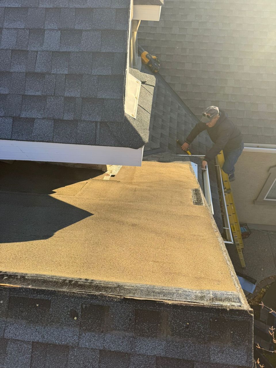 Roofer working at the eave of a low-slope roof section during a repair