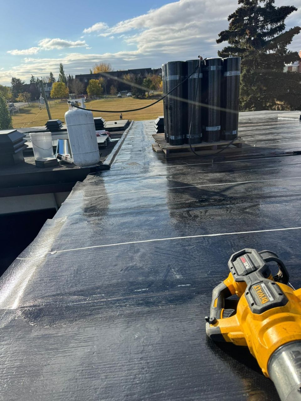 SBS base sheet installed with rolls of cap sheet staged on a flat roof